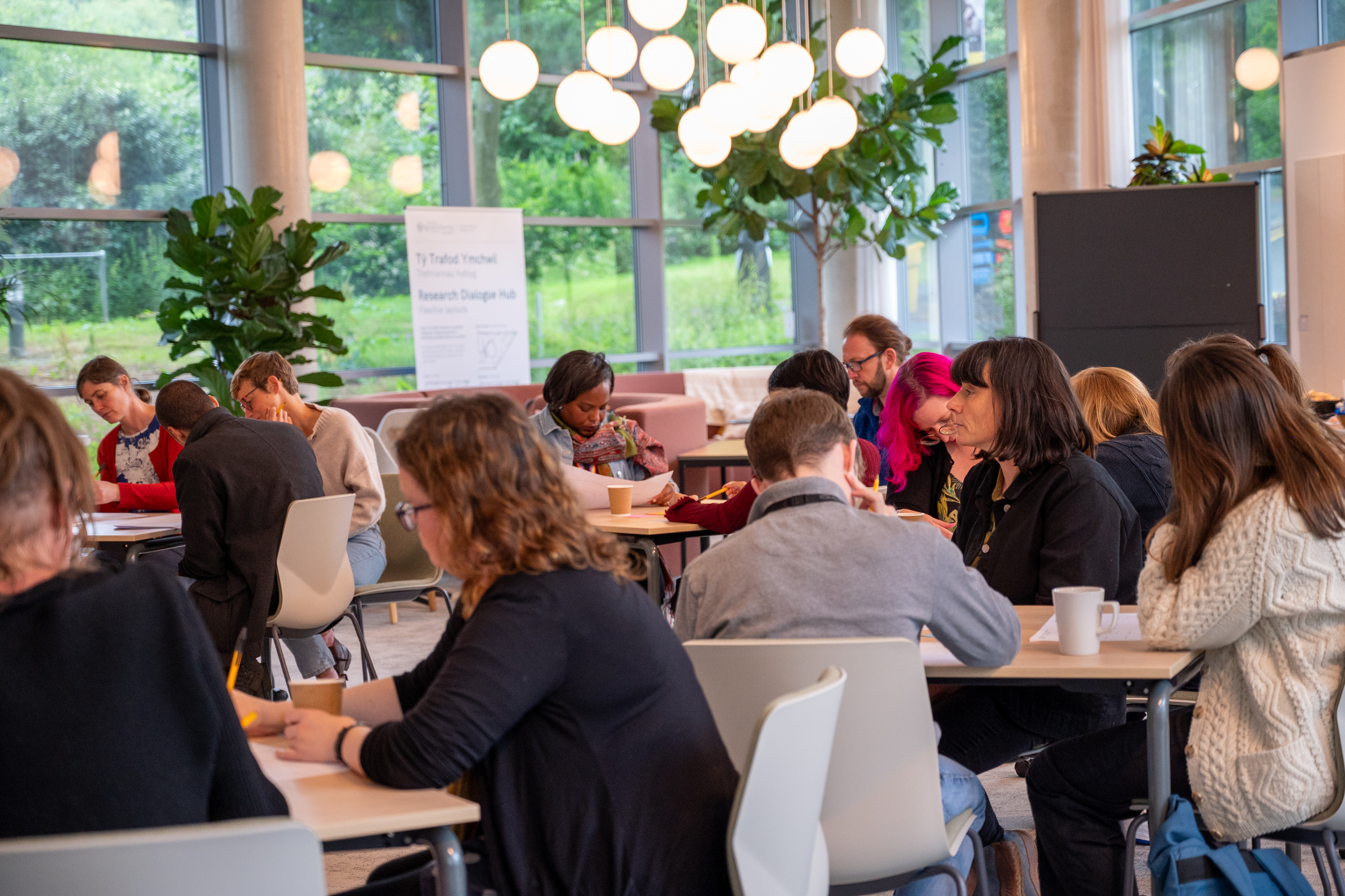 Researchers who took part in Aberystwyth University's AberCollab programme gather around tables to discuss their projects.