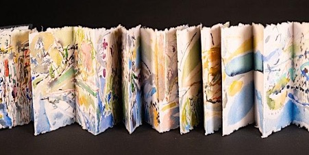 A long narrow piece of card folded in a concertina style as pages of a book and colourfully decorated